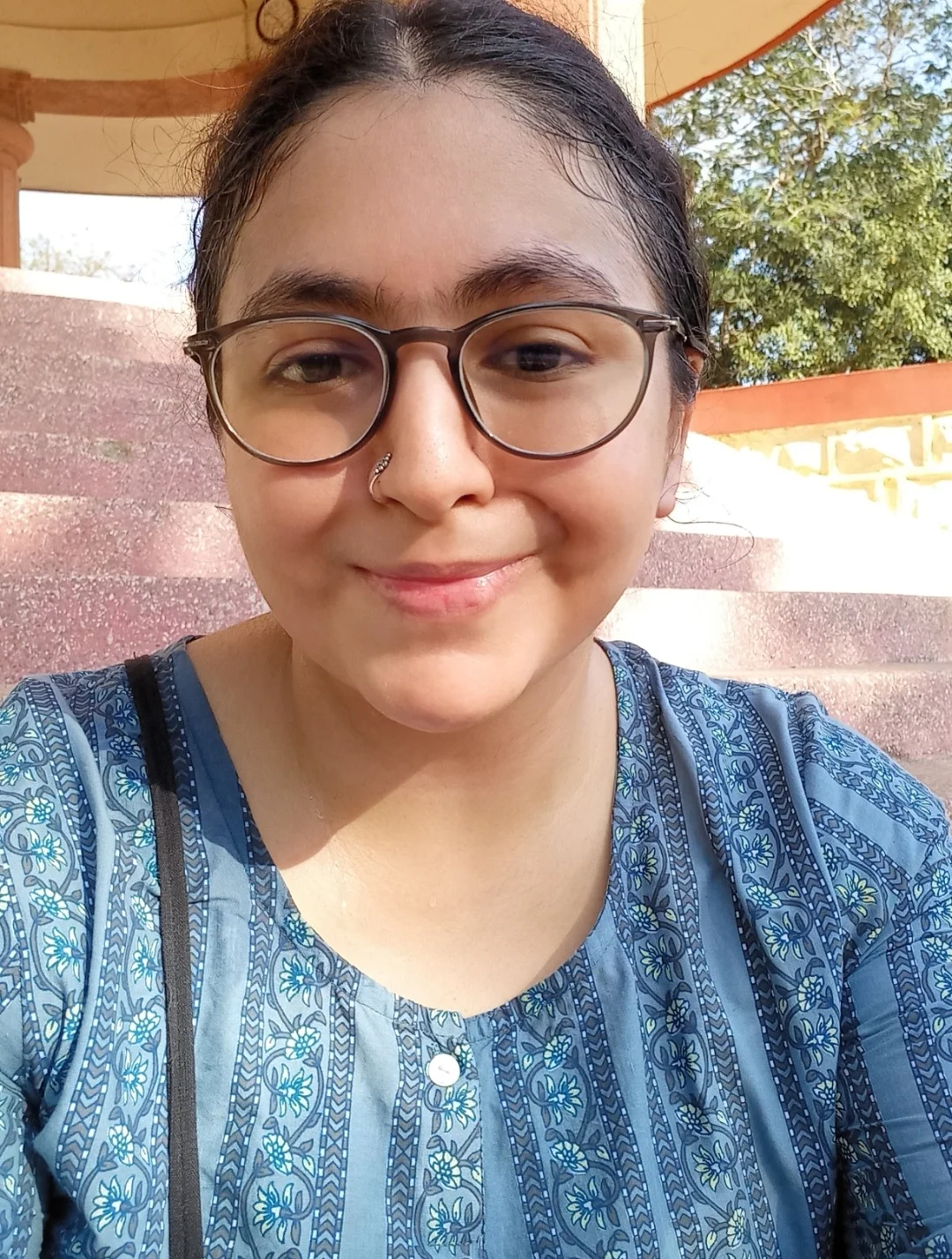 Portrait of the author Kunjana Parashar. Kunjana is wearing brown glasses and a blue blouse with a flowery pattern.